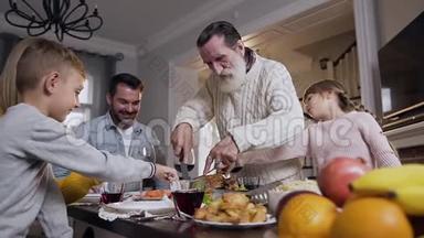 感恩节庆祝期间，一家人在餐桌上闲荡，祖父在餐桌上切烤火鸡